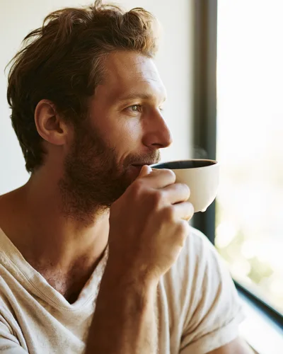Man Drinking Coffee While Looking Out A Window