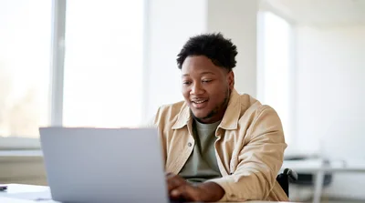 Young Black Man Working On Laptop In Bright Office