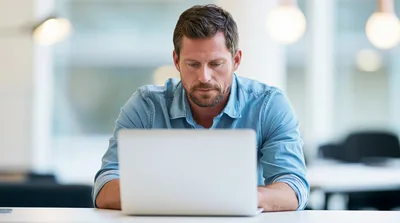 Focused Businessman Working On Laptop In Modern Office