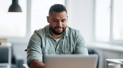 Young Man Working On Laptop In Bright Office