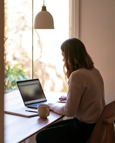 Woman Working On Laptop At Home Office Desk