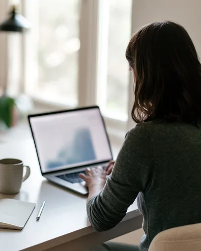 Woman Working On Laptop At Home Office Desk