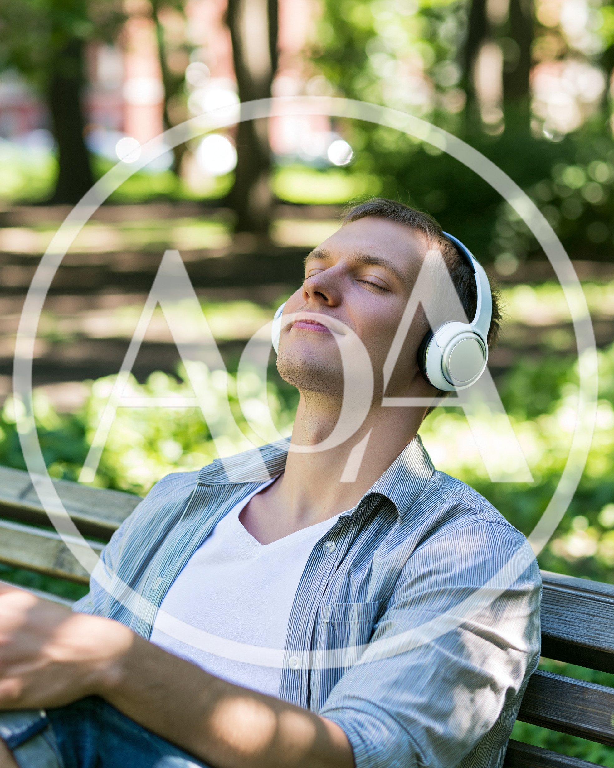 Young Man Relaxing With Headphones On Park Bench
