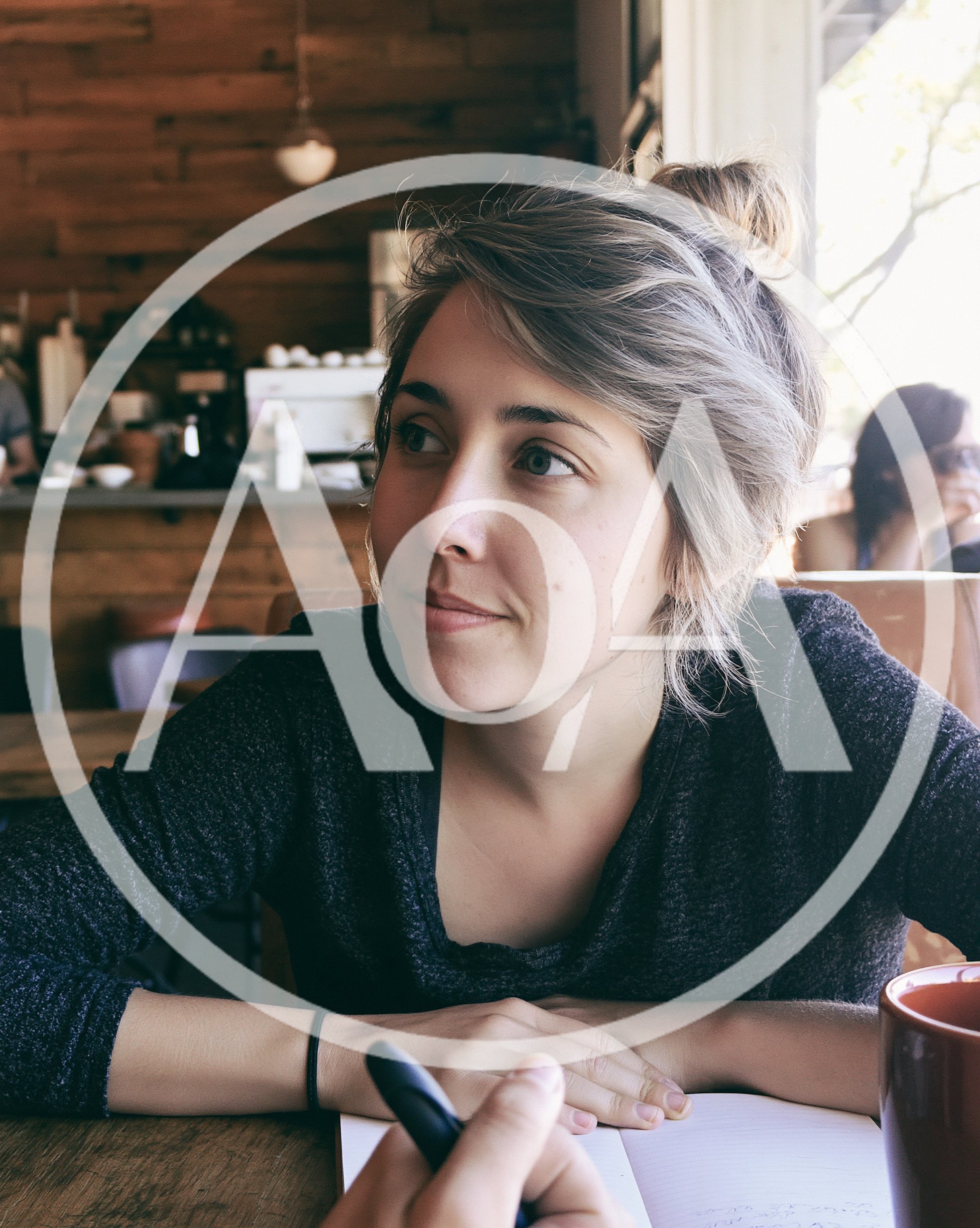 Young Woman Sitting At Cafe Table With Notebook