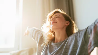 Young Woman Stretching Arms In Sunlight