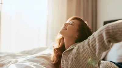 Young Woman Stretching Happily In Bed During Morning Sunlight