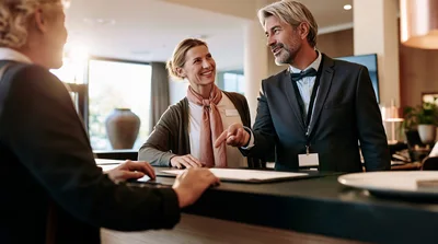 Hotel Receptionists Assisting A Guest At The Front Desk