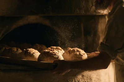 Artisan Baker Placing Fresh Bread Loaves Into Stone Oven