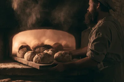 Artisan Baker Placing Sourdough Loaves Into Wood Fired Oven