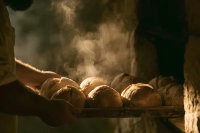 Baker Removing Freshly Baked Sourdough Loaves From Oven