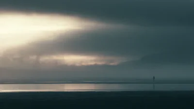 Lone Person Standing On A Misty Beach At Twilight