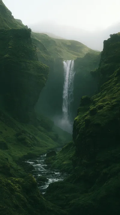 Majestic Waterfall Flowing Through A Lush Green Mossy Canyon