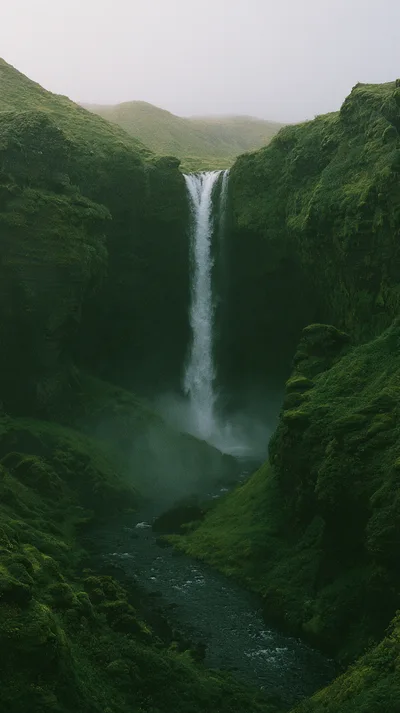 Majestic Waterfall Cascading Through Lush Green Icelandic Canyon