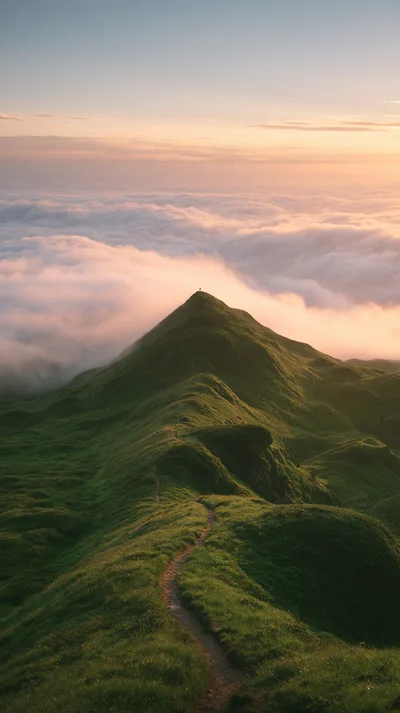 Lone Hiker Standing Atop A Green Mountain Peak