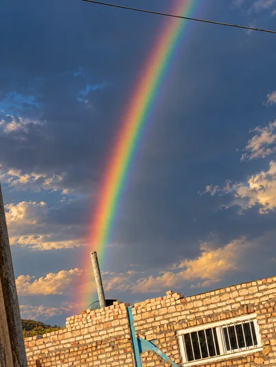 Vibrant Rainbow Appearing Above A Partially Constructed Brick Building
