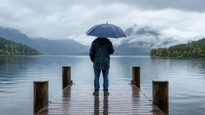 Man Standing On A Wooden Pier With An Umbrella