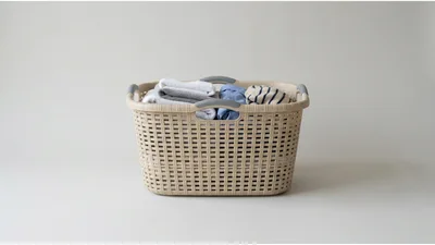 Beige Plastic Laundry Basket Filled With Folded Clothes