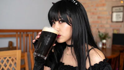 Young Woman Drinking Dark Beer in a Pub