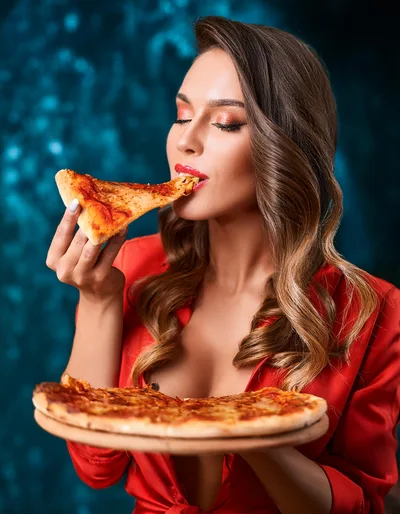 Beautiful Woman Eating Pizza Slice Against Blue Background