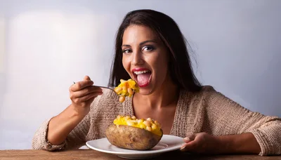 Woman Eating Baked Potato With Beans And Cheese