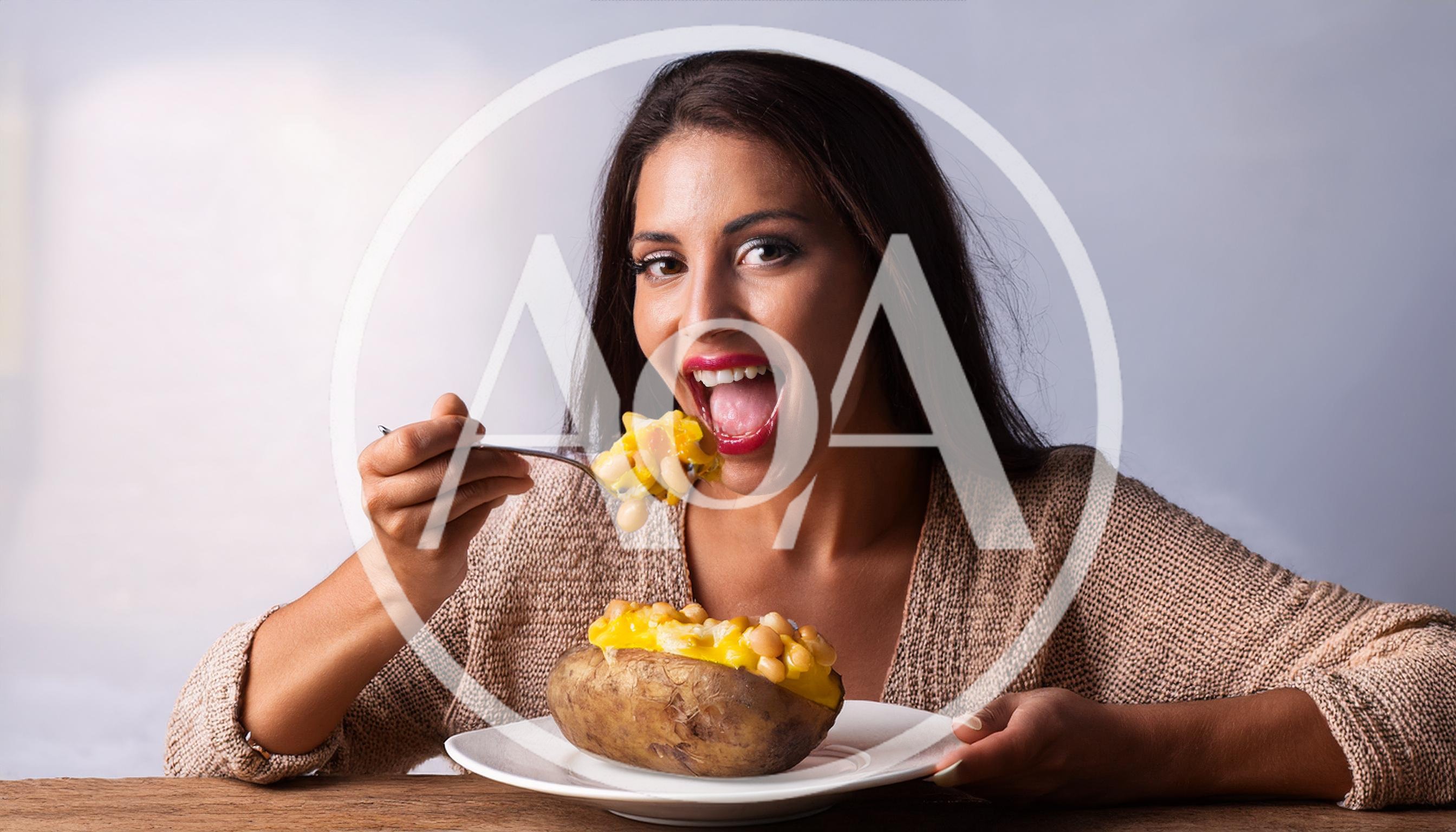Woman Eating Baked Potato With Beans And Cheese