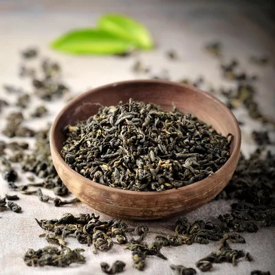 Dried Green Tea Leaves In A Rustic Clay Bowl