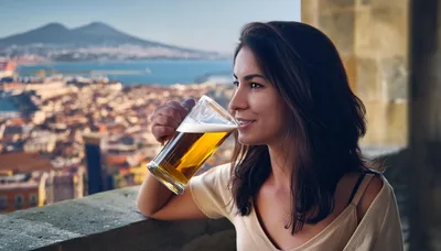 Young Woman Drinking Beer Overlooking Naples Cityscape