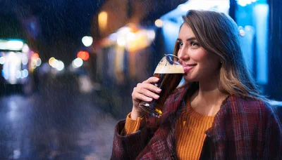 Young Woman Drinking Dark Beer Outdoors In The Rain