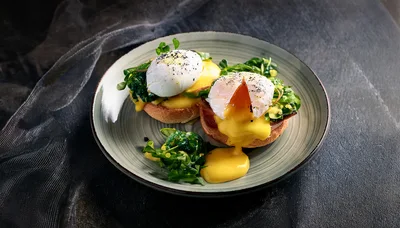 Two Eggs Benedict With Hollandaise Sauce On A Plate