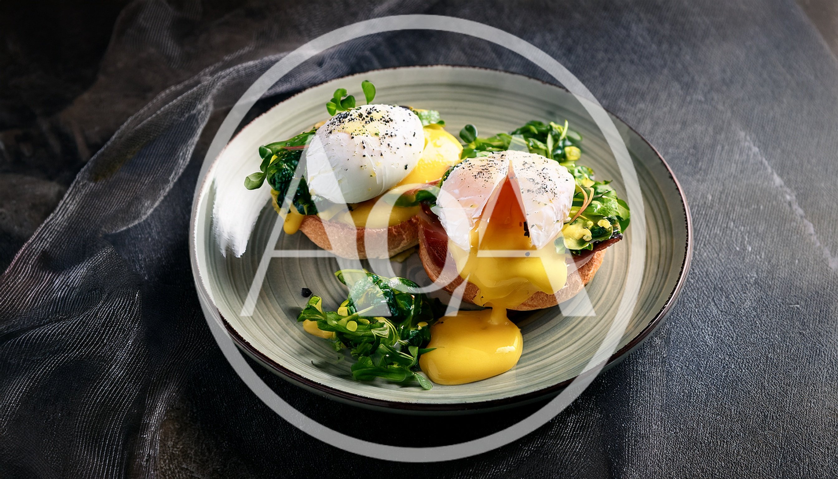 Two Eggs Benedict With Hollandaise Sauce On A Plate