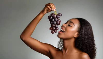 Young Woman Holding And Eating Fresh Purple Grapes