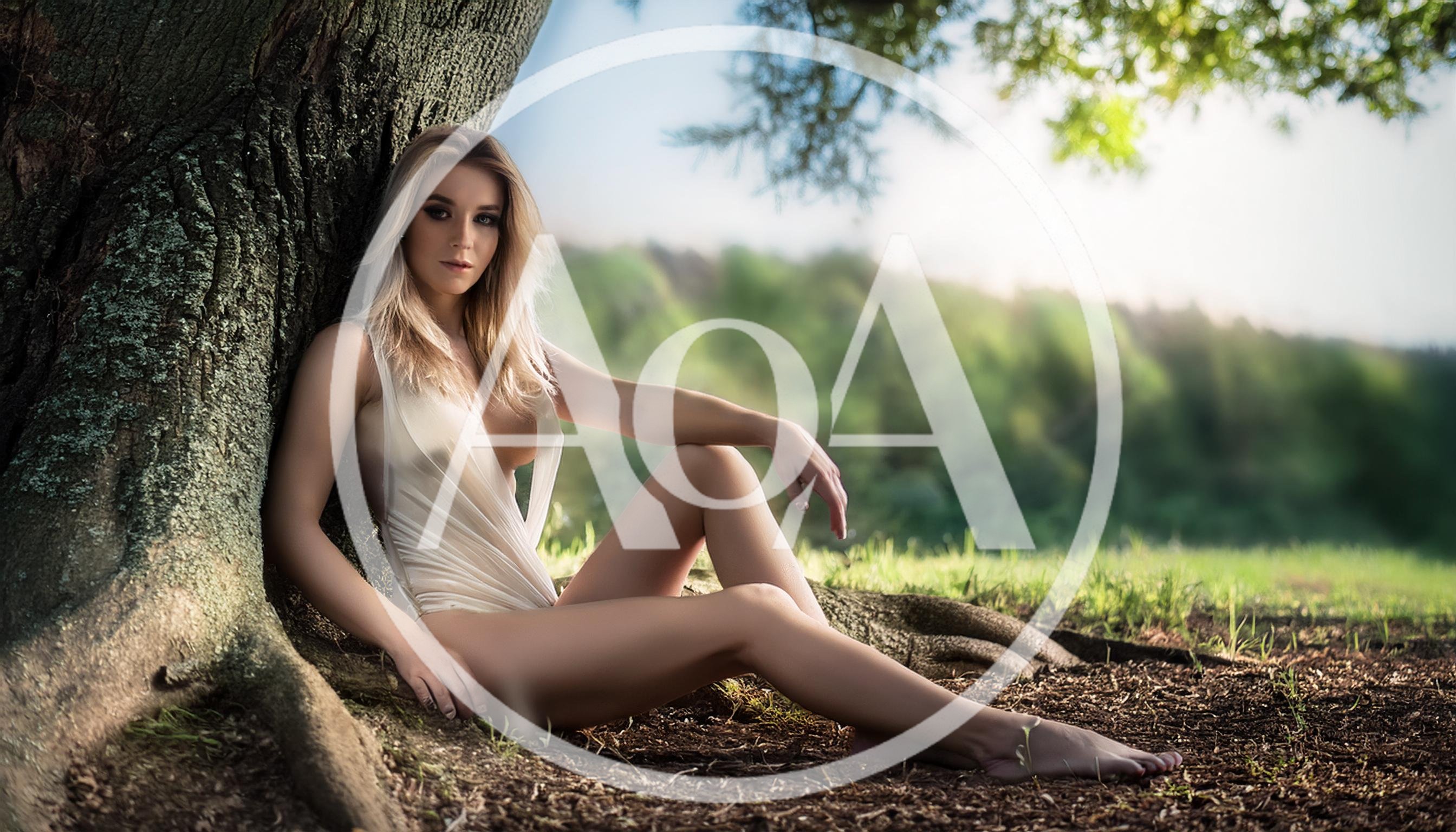 Blonde Woman Sitting Against A Tree In Nature