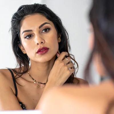 Woman Looking At Her Reflection In A Mirror