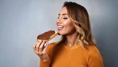 Young Woman Enjoying A Slice Of Chocolate Spread Toast
