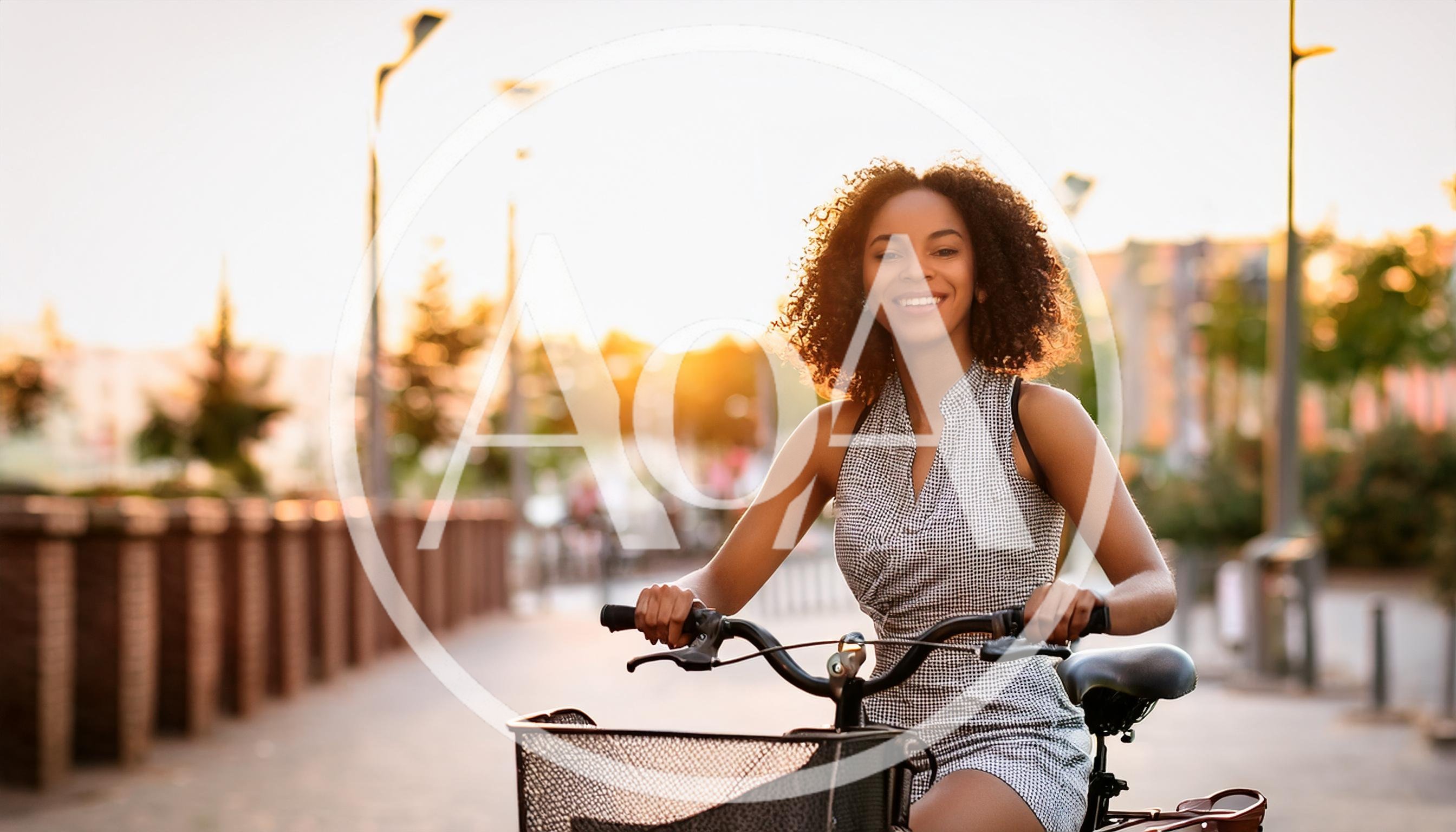 Young Woman Riding A Bicycle At Sunset