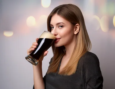 Young Woman Drinking Dark Beer From A Glass