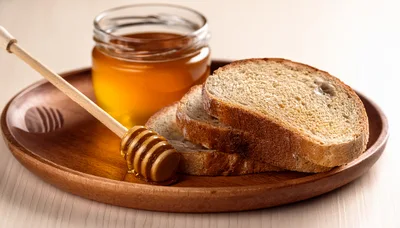 Honey Dipper With Slices Of Bread On Wooden Plate