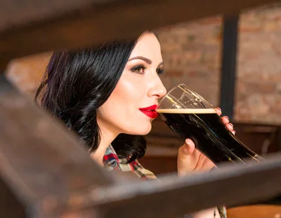 Woman Drinking Dark Beer in a Pub