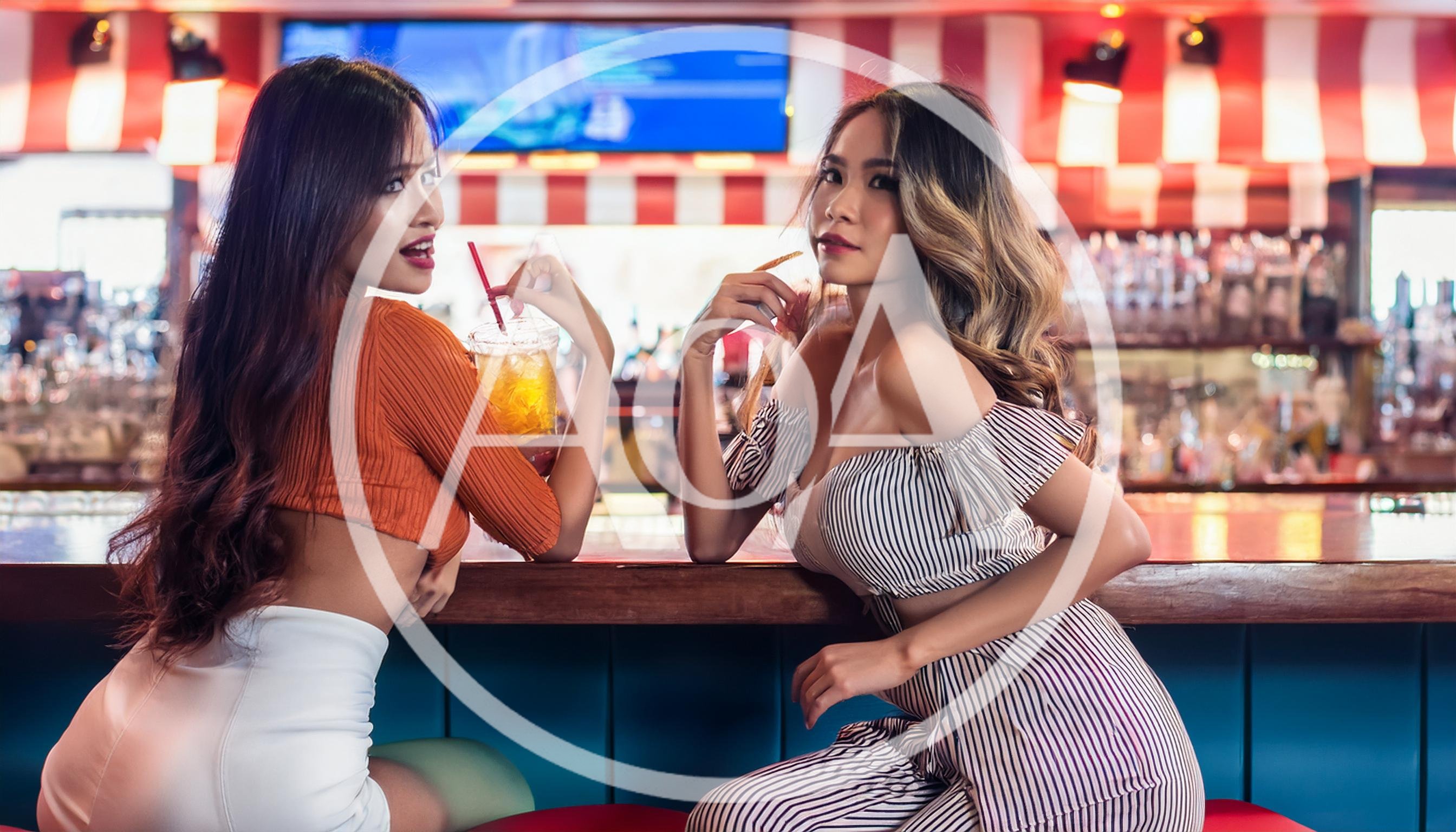 Two Young Women Enjoying Drinks at a Bar
