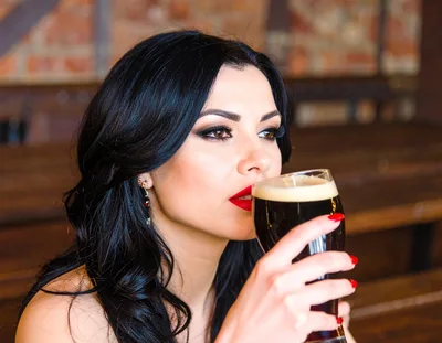Beautiful Woman Drinking Dark Beer in a Pub