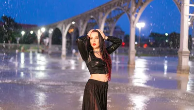 Woman Posing In Rain Under Illuminated Arches