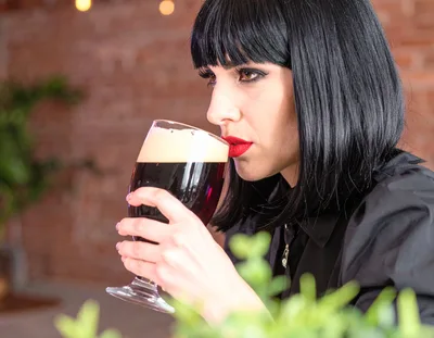 Woman With Dark Hair Drinking Dark Beer
