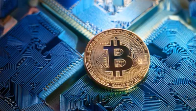 Gold Bitcoin Coin Resting On Blue Circuit Board