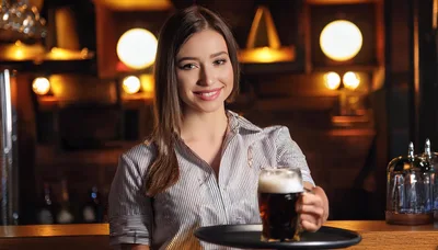 Smiling Female Bartender Serving Dark Beer In Pub