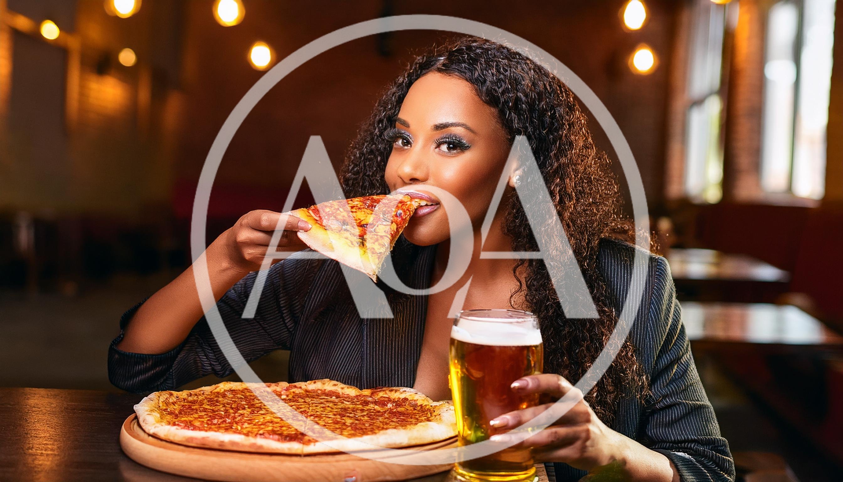 Young Woman Eating Pizza and Drinking Beer in Restaurant