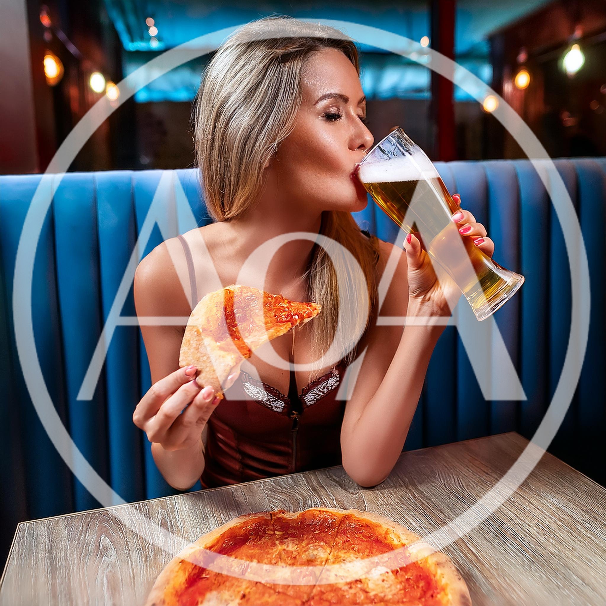 Young Woman Eating Pizza And Drinking Beer In Restaurant