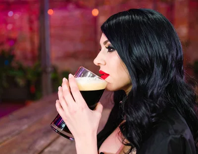 Woman Drinking Dark Beer In A Bar