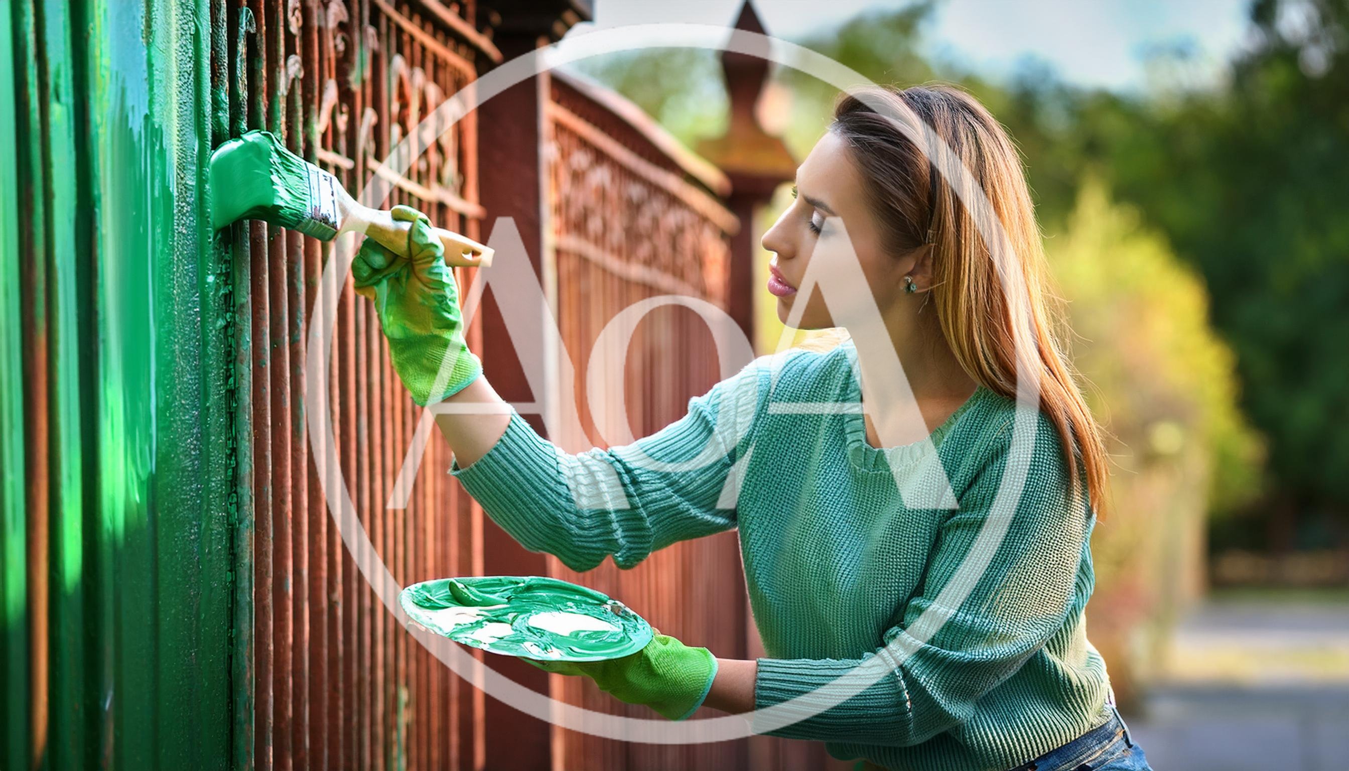 Young Woman Painting A Metal Fence Green