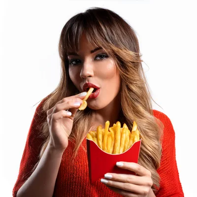Young Woman Eating French Fries From A Red Carton