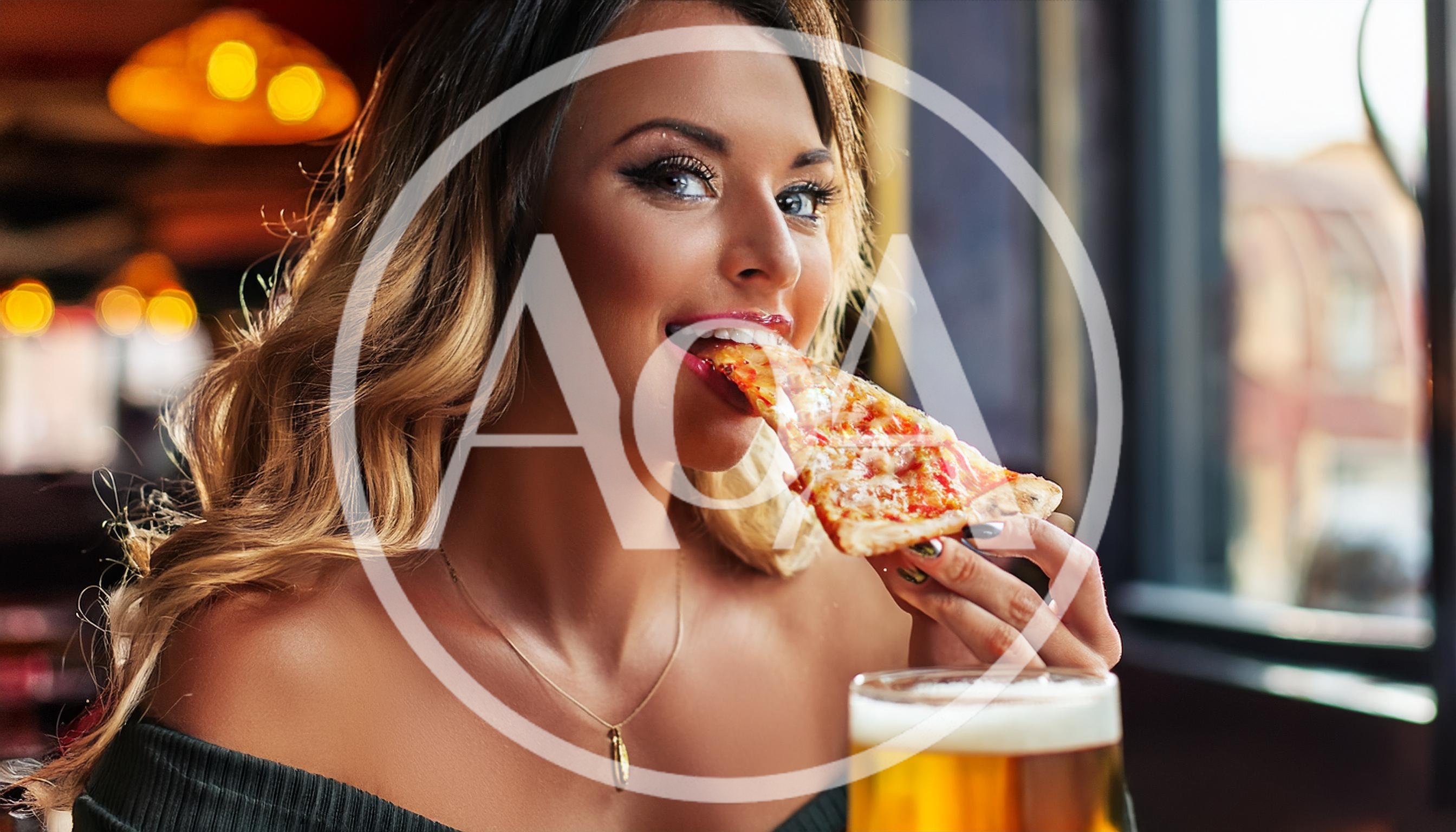 Young Woman Eating Pizza Slice In A Restaurant